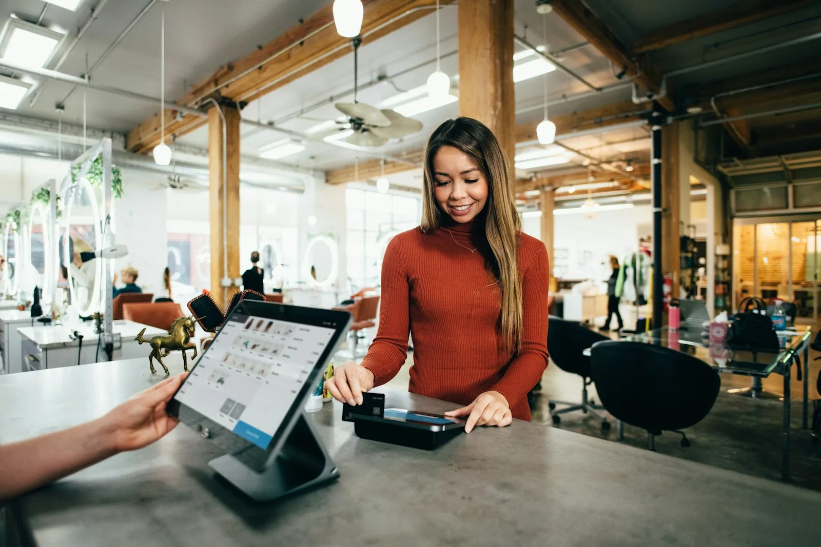 A salon owner taking a card payment at the front desk of her studio
